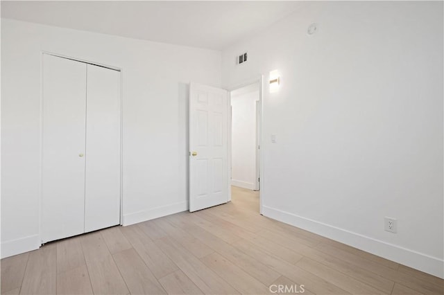 unfurnished bedroom with a closet and light hardwood / wood-style floors