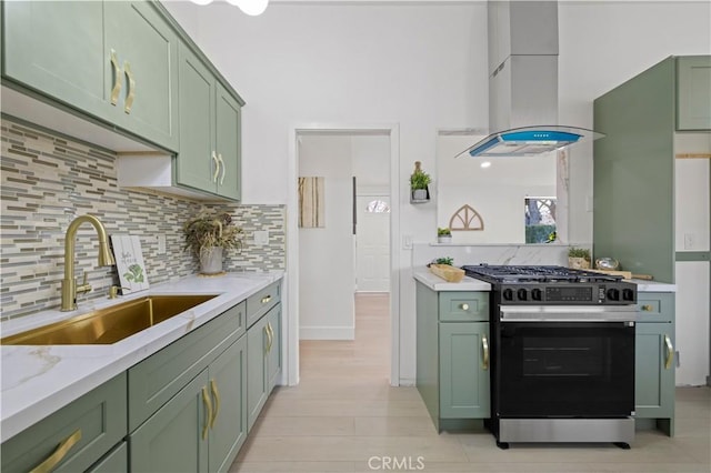 kitchen featuring stainless steel gas stove, sink, green cabinets, and island range hood