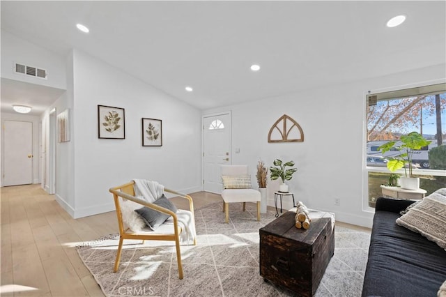 living room featuring lofted ceiling and light hardwood / wood-style floors