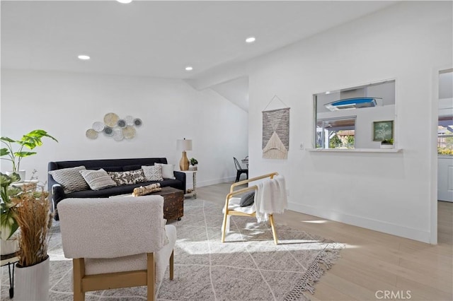 living room featuring lofted ceiling and light hardwood / wood-style floors