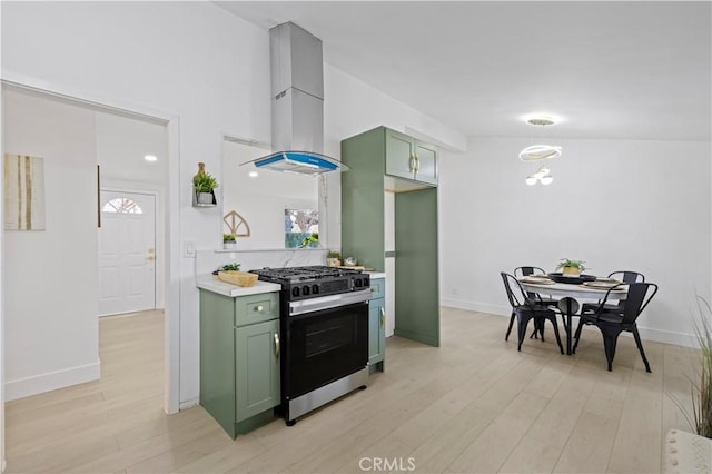 kitchen with green cabinetry, island range hood, gas stove, and light hardwood / wood-style floors