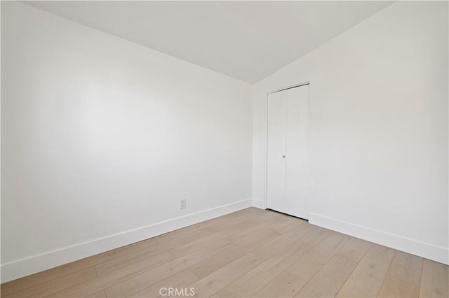 unfurnished room with lofted ceiling and light hardwood / wood-style floors