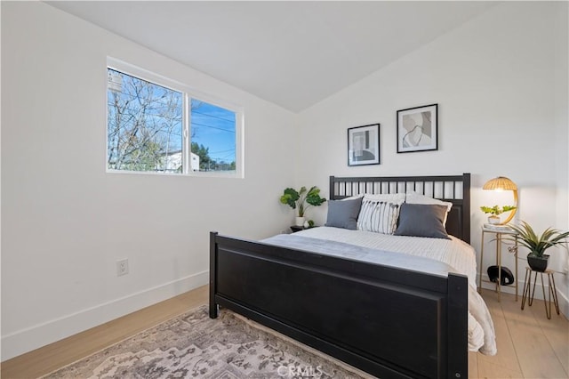 bedroom featuring light wood-type flooring and vaulted ceiling