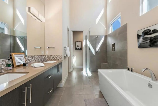 bathroom with plus walk in shower, decorative backsplash, tile patterned floors, and vanity