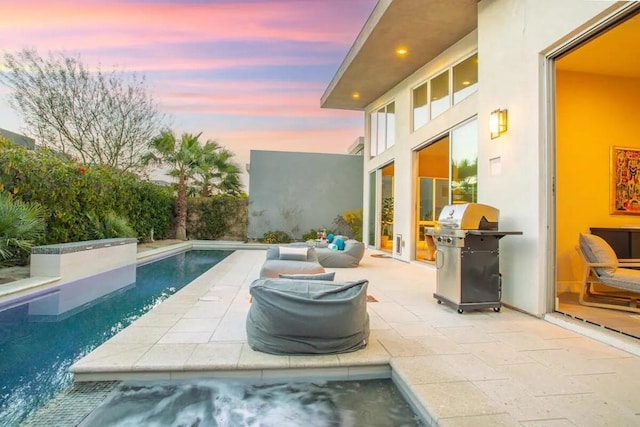 pool at dusk with a patio area and area for grilling