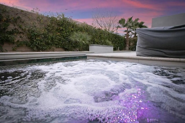 pool at dusk with a jacuzzi