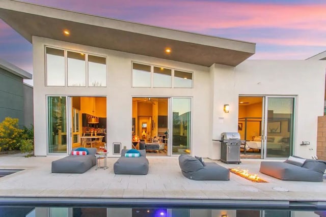 back house at dusk featuring a patio area