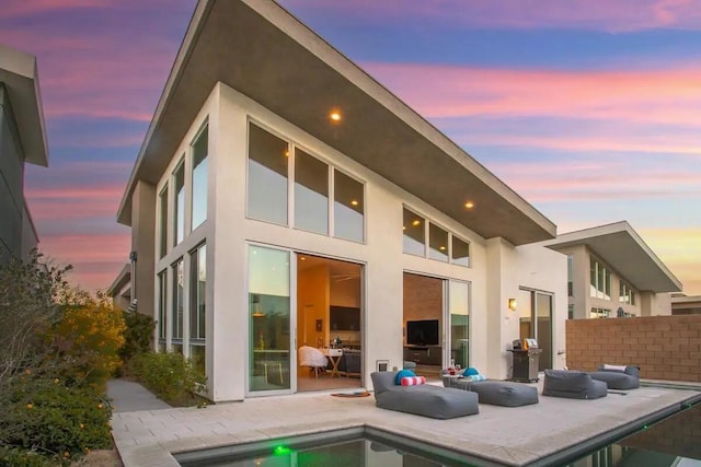 back house at dusk featuring a patio