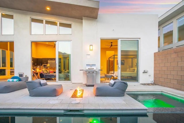 back house at dusk featuring a patio area and a fire pit