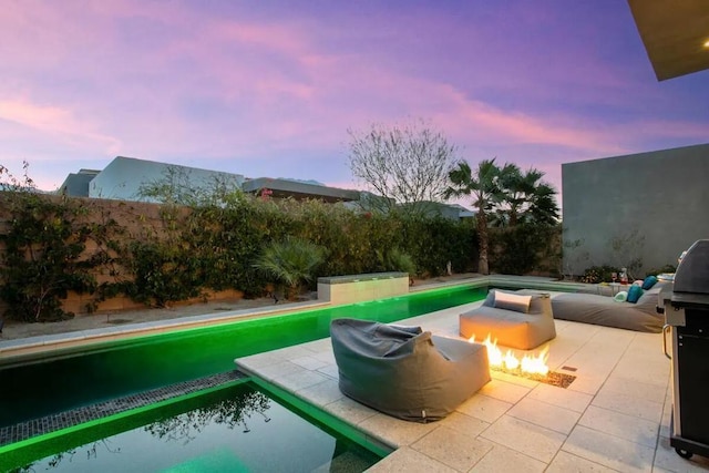 pool at dusk featuring an outdoor fire pit and area for grilling