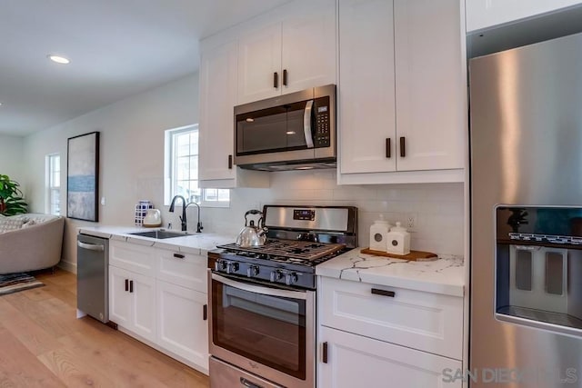 kitchen with stainless steel appliances, white cabinetry, and sink