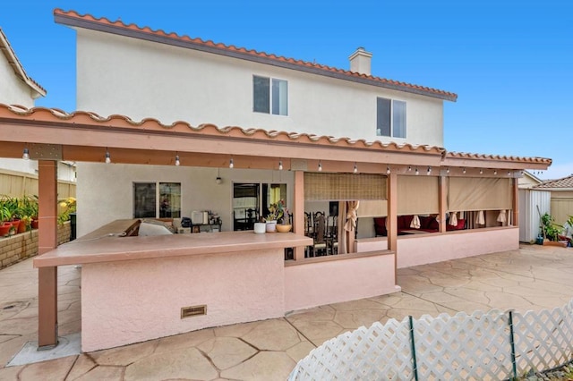 back of property featuring an outdoor kitchen and a patio