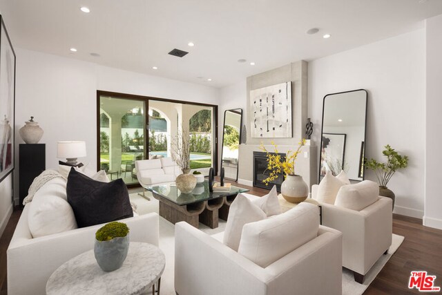 living room featuring dark wood-type flooring and a large fireplace