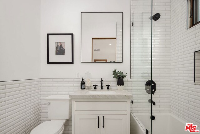 full bathroom featuring toilet, vanity, tile walls, and tiled shower / bath combo