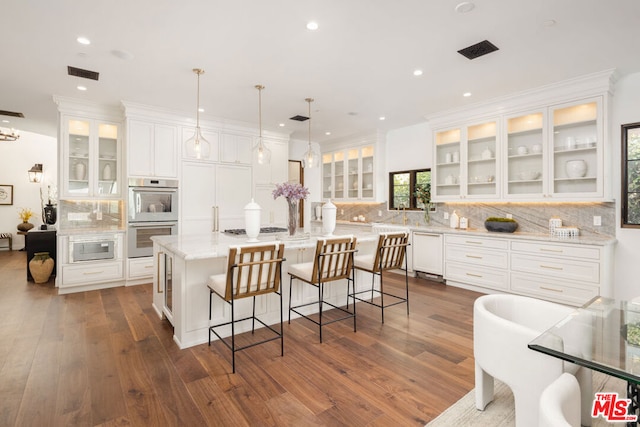 kitchen featuring pendant lighting, white cabinets, a center island with sink, and stainless steel appliances