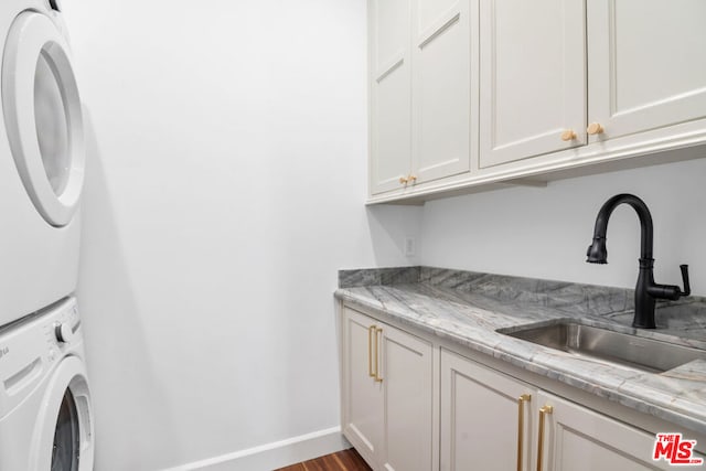 laundry room featuring stacked washer / drying machine, sink, and cabinets