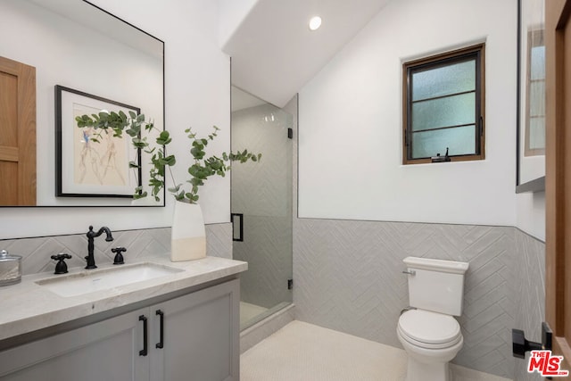 bathroom featuring a shower with shower door, vanity, tile walls, and toilet