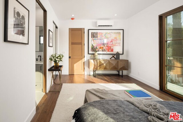 bedroom with sink, dark hardwood / wood-style flooring, access to outside, and a wall mounted air conditioner