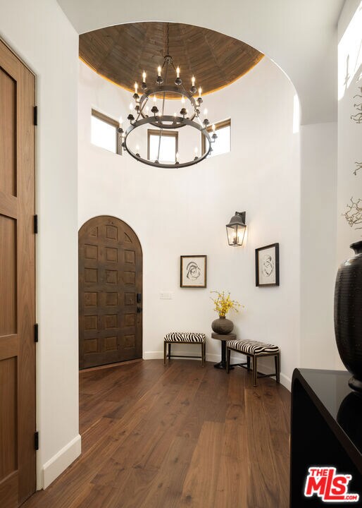 entryway with a high ceiling, dark hardwood / wood-style floors, and an inviting chandelier