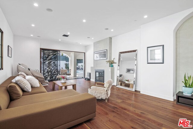 living room with dark wood-type flooring and a large fireplace