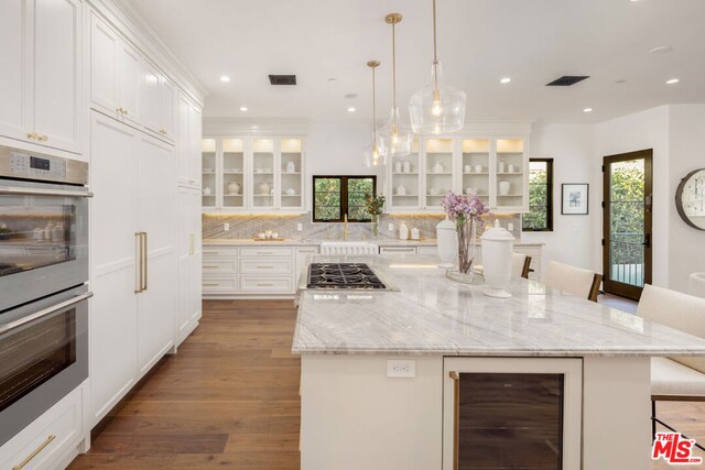 kitchen with wine cooler, white cabinets, a kitchen bar, and a spacious island