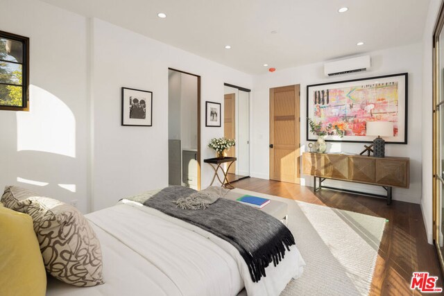 bedroom with dark wood-type flooring and a wall mounted AC