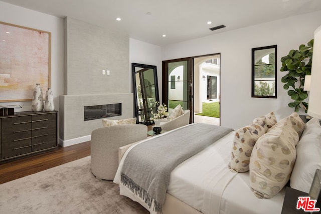 bedroom with dark wood-type flooring and a large fireplace