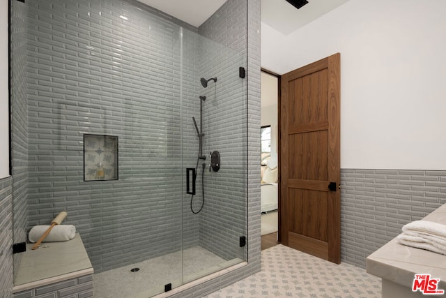 bathroom featuring tile walls and a shower with door