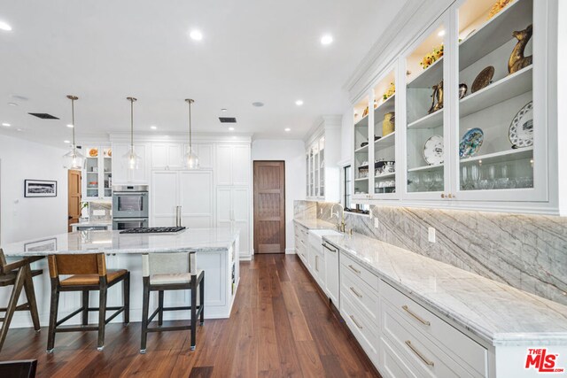 kitchen featuring backsplash, a spacious island, pendant lighting, double oven, and white cabinets