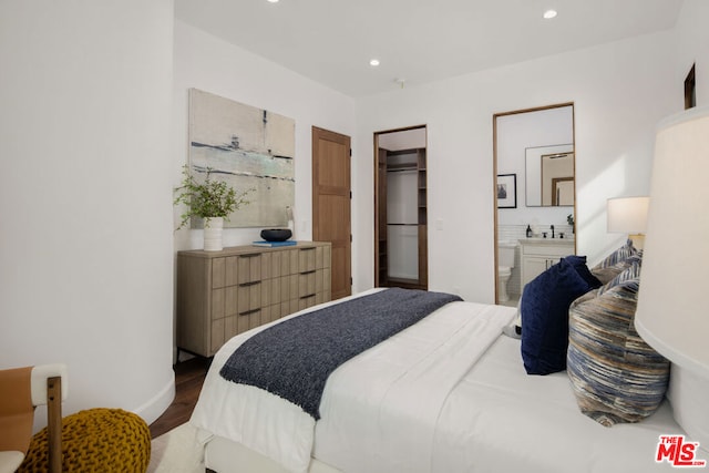 bedroom featuring sink, dark wood-type flooring, a spacious closet, connected bathroom, and a closet