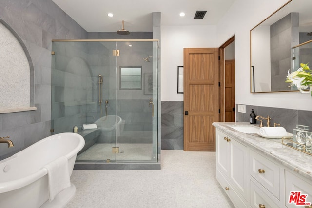 bathroom with shower with separate bathtub, tile walls, and vanity