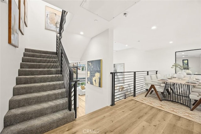 stairs with vaulted ceiling and hardwood / wood-style floors