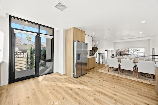 kitchen with plenty of natural light, stainless steel fridge with ice dispenser, and light wood-type flooring