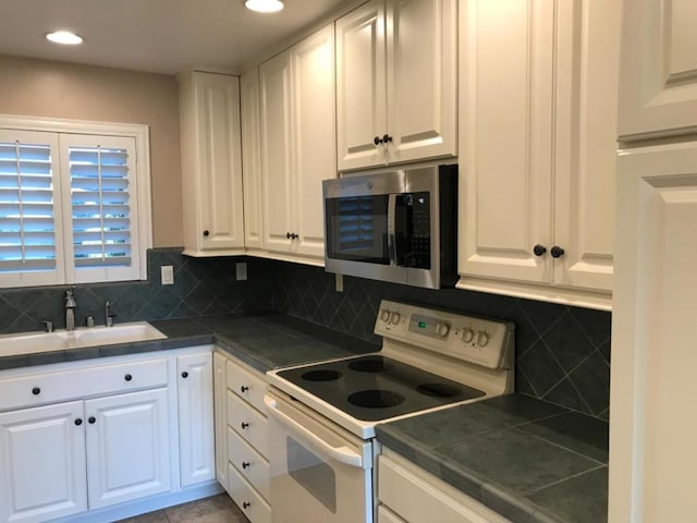 kitchen with sink, electric range, and white cabinetry