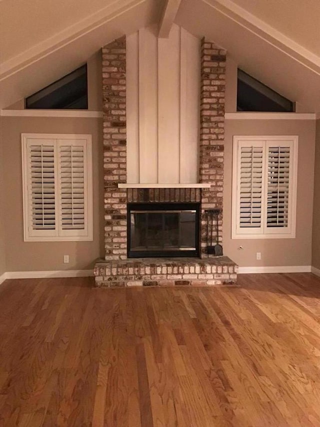 unfurnished living room featuring hardwood / wood-style floors, a brick fireplace, and lofted ceiling with beams