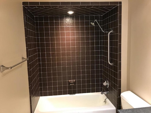 bathroom with toilet and tiled shower / bath combo