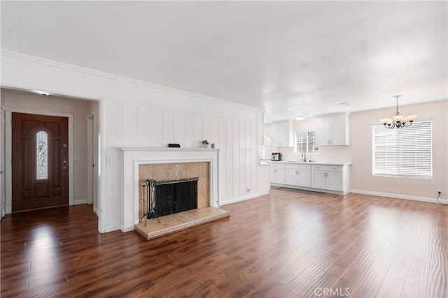 unfurnished living room featuring a fireplace, sink, dark hardwood / wood-style flooring, and a chandelier