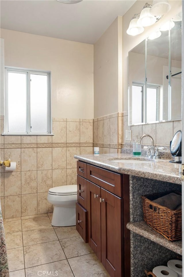 bathroom with toilet, tile walls, tile patterned floors, and vanity