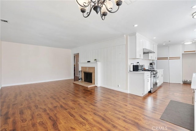 unfurnished living room featuring a tile fireplace, a chandelier, and hardwood / wood-style floors