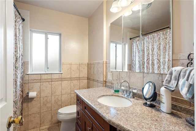 bathroom featuring toilet, vanity, and tile walls