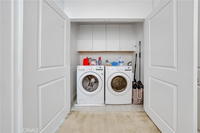 clothes washing area with cabinets, washer and dryer, and light tile patterned flooring