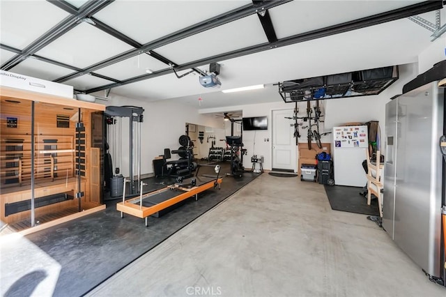 garage with white fridge, ceiling fan, a garage door opener, and stainless steel refrigerator