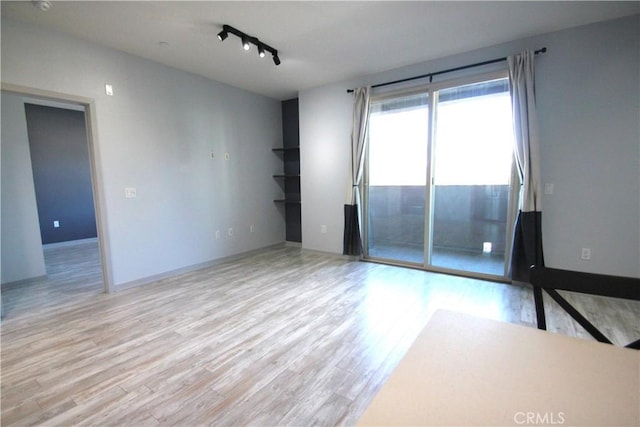 spare room with track lighting and light hardwood / wood-style flooring