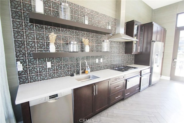 kitchen with light parquet floors, island range hood, stainless steel appliances, dark brown cabinetry, and sink