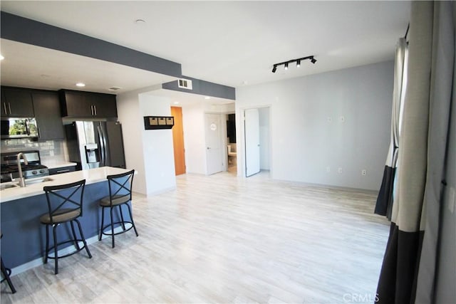 kitchen featuring stainless steel appliances, decorative backsplash, a kitchen breakfast bar, sink, and dark brown cabinets