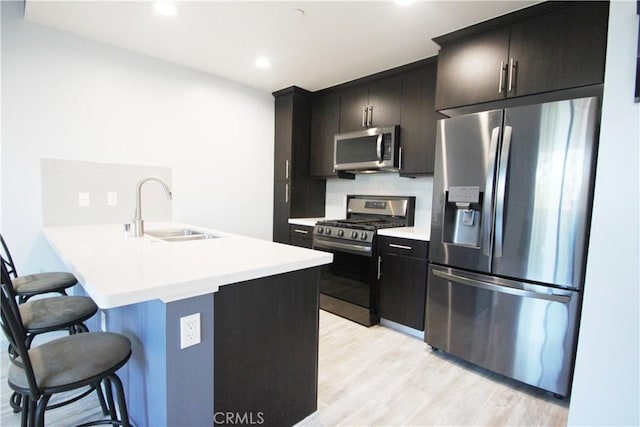 kitchen featuring backsplash, kitchen peninsula, a kitchen bar, sink, and stainless steel appliances