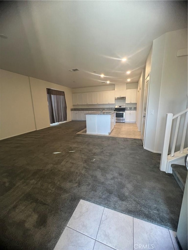 kitchen with stainless steel range, light colored carpet, white cabinets, and a center island