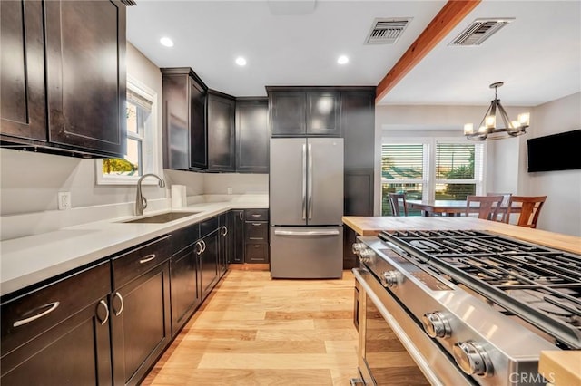 kitchen featuring an inviting chandelier, sink, hanging light fixtures, dark brown cabinetry, and stainless steel appliances