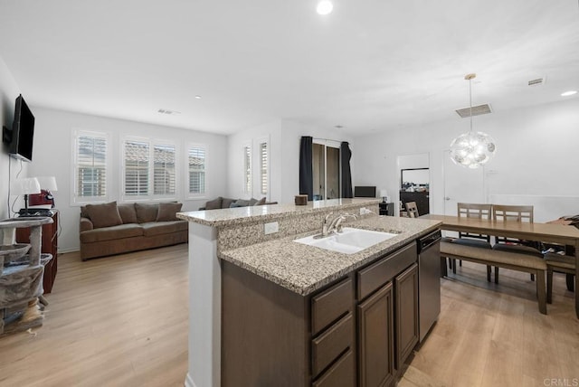 kitchen with dark brown cabinets, hanging light fixtures, stainless steel dishwasher, light hardwood / wood-style flooring, and sink