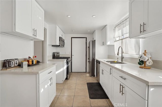 kitchen featuring appliances with stainless steel finishes, white cabinetry, light tile patterned floors, and sink